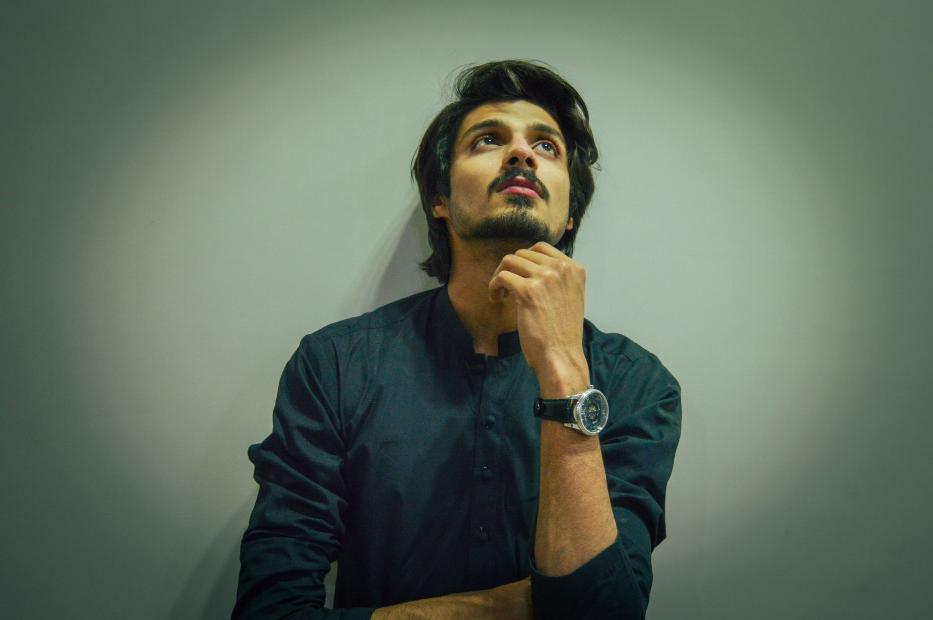 Portrait of a thoughtful man pondering indoors. Cool tone, introspective mood.