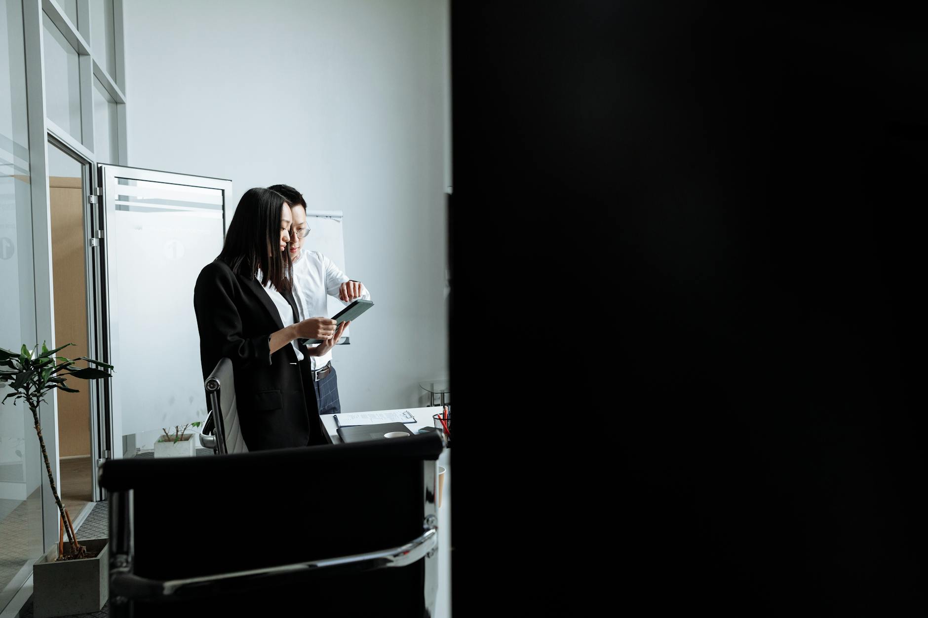 Two young professionals collaborating and discussing work in a modern office setting.