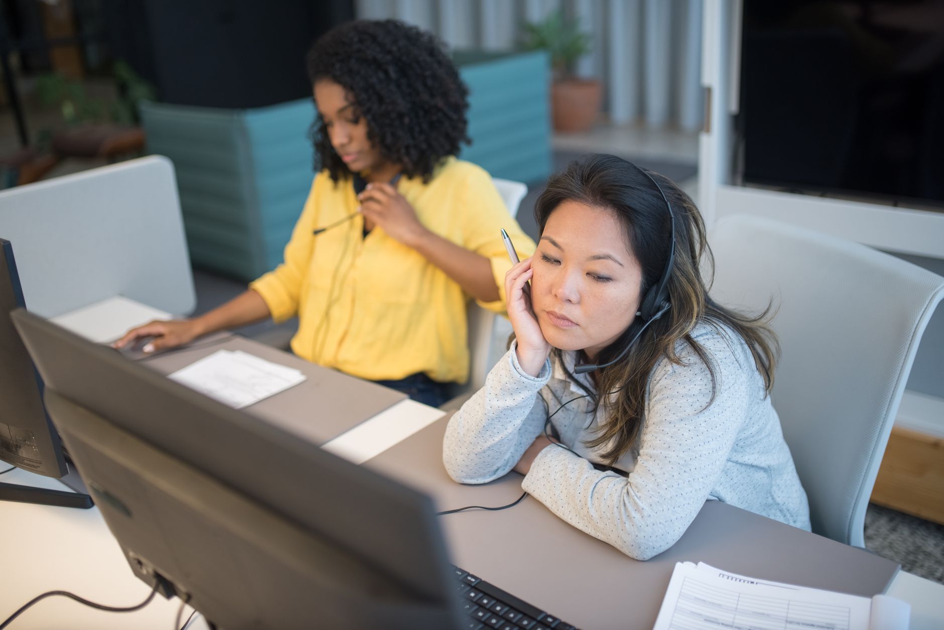 Two women focused on work in a modern call center office environment.