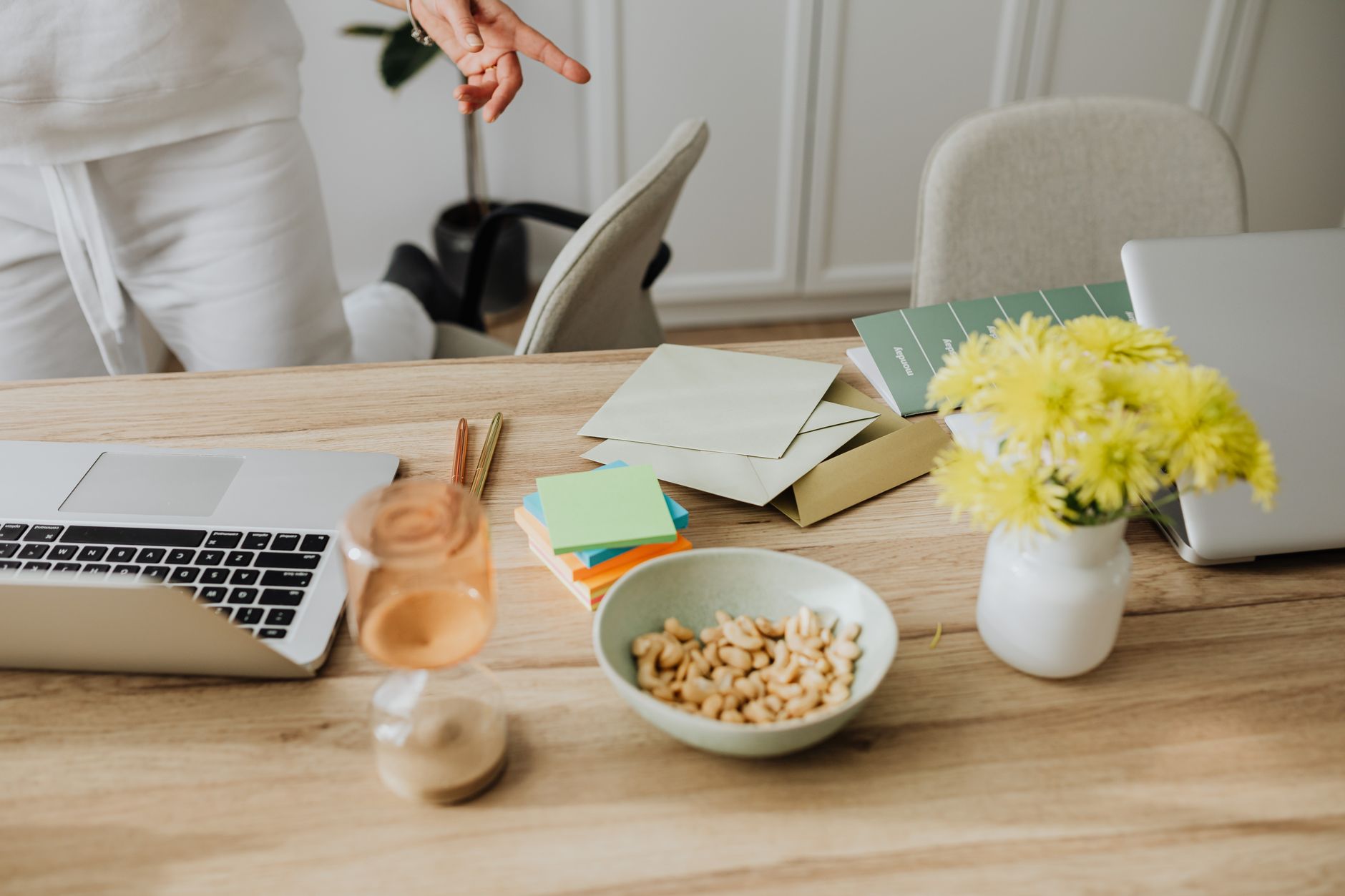 Warm and inviting home office setup with snacks and vibrant flowers on a wooden desk.