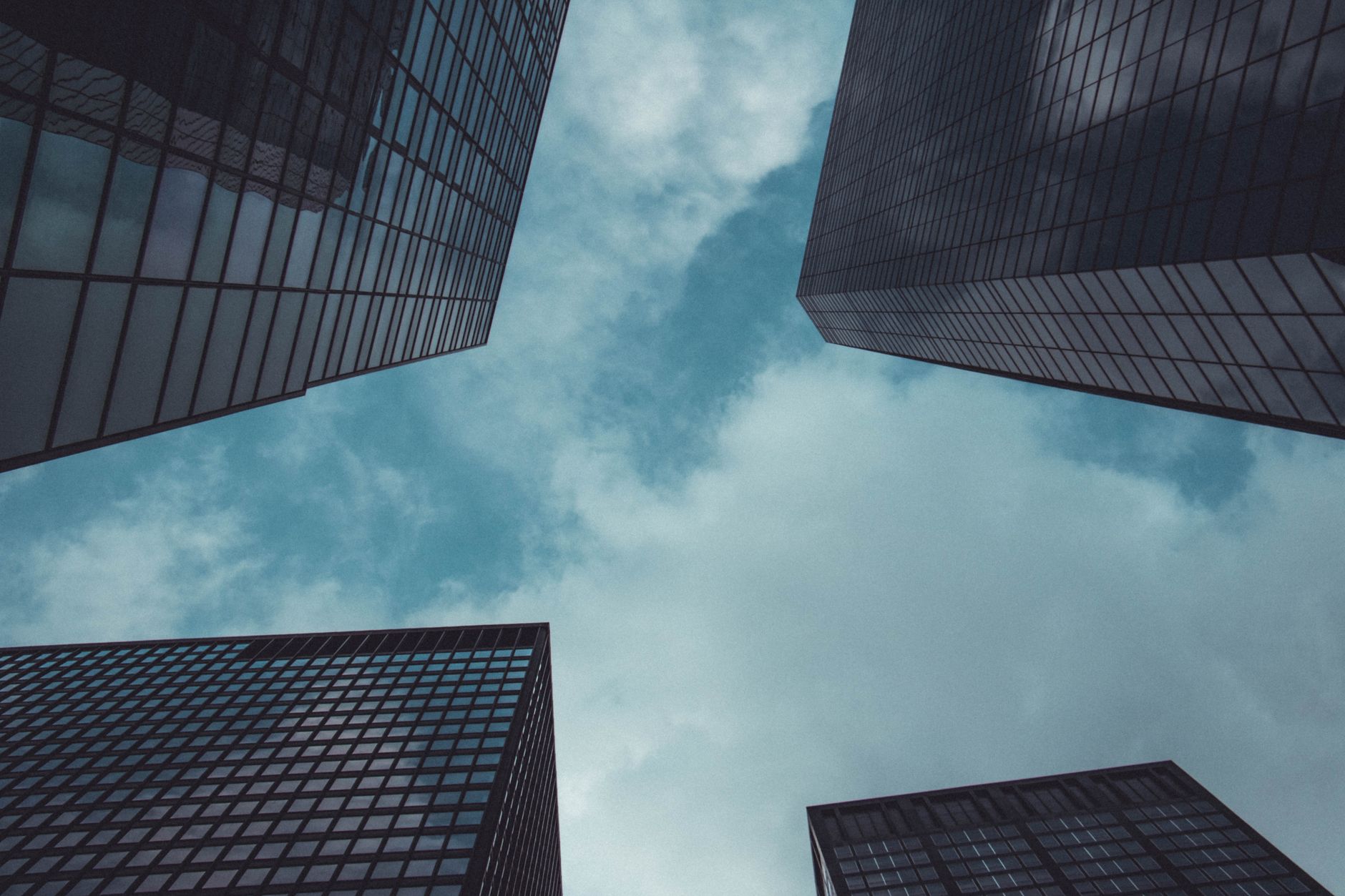 Low angle view of modern skyscrapers in New York City against a cloudy sky.
