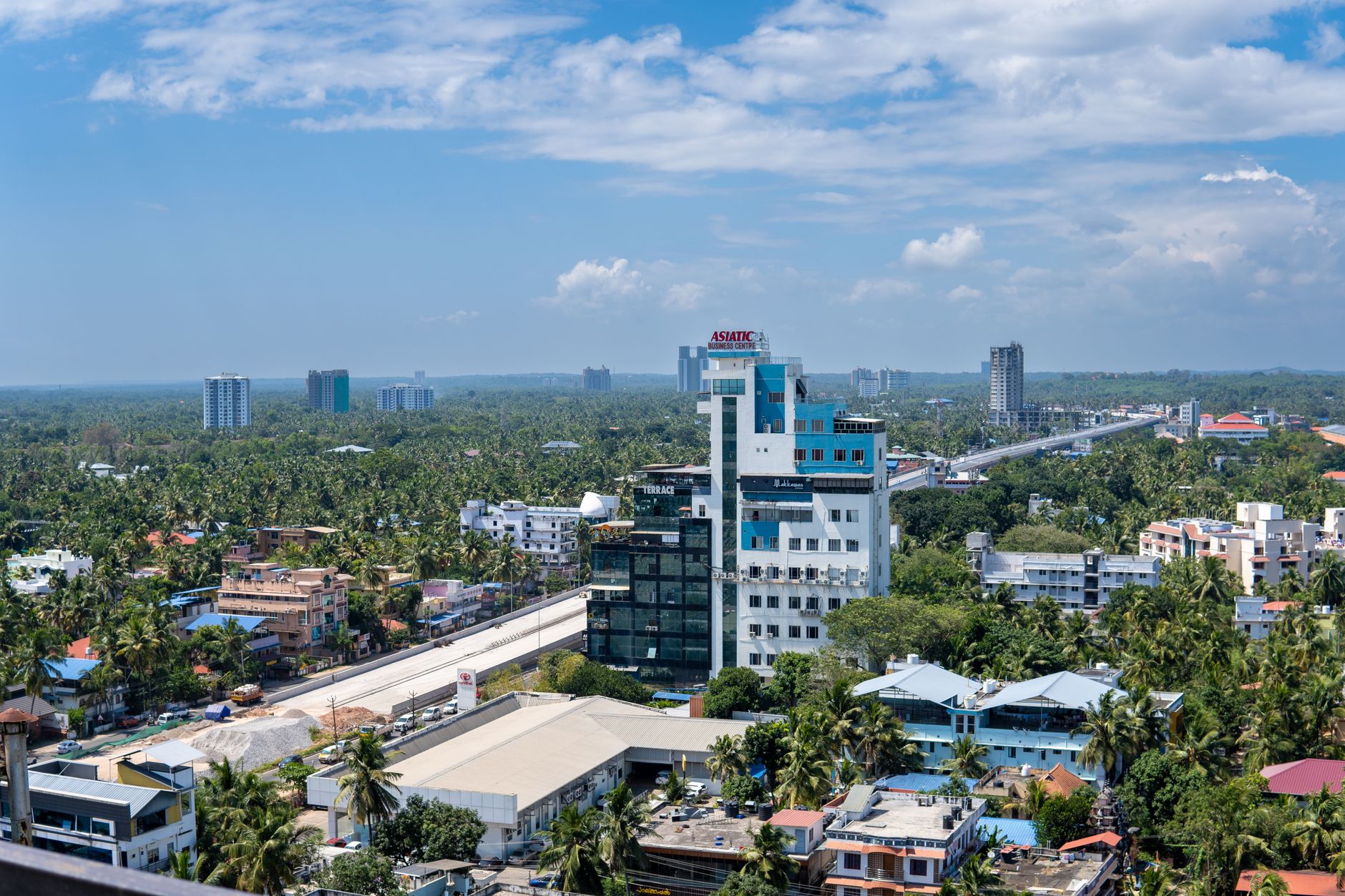 Panoramic aerial view of Thiruvananthapuram cityscape with lush greenery and modern architecture.